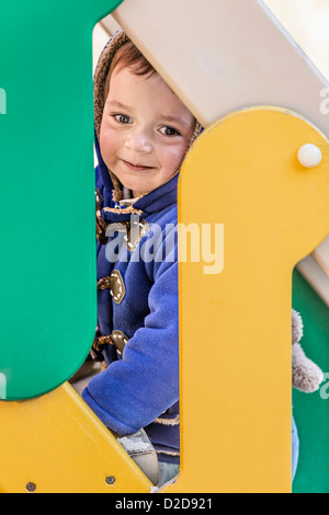 Un giovane ragazzo salire le scale di una diapositiva in un parco giochi Foto Stock