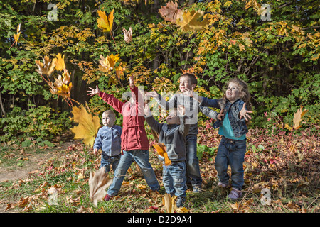 Cinque ragazzi cercando di catturare la caduta di foglie di autunno Foto Stock