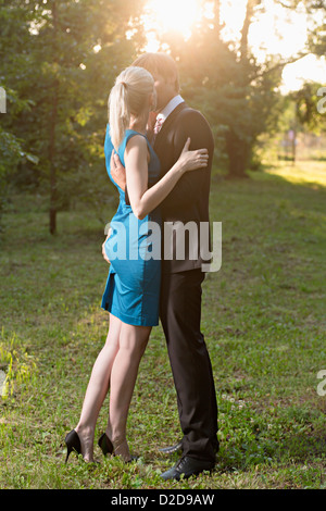 Un ambiente elegantemente vestito uomo baciare la sua ragazza appassionatamente mentre schiacciano il suo fondo Foto Stock