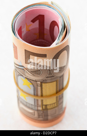 50 Euro nota su un rotolo di denaro di Euro arrotolato con una fascia elastica su uno sfondo bianco per illustrare il risparmio di denaro concetto. Europa Foto Stock