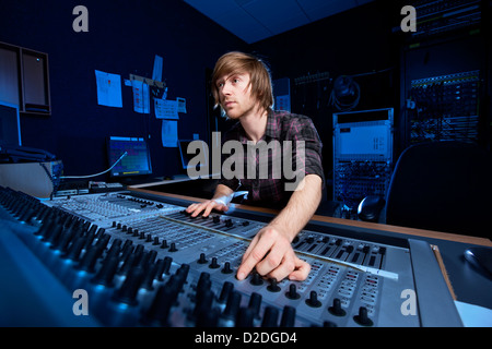 Uomo che utilizza un suono miscelazione scrivania in uno studio di registrazione. Foto Stock