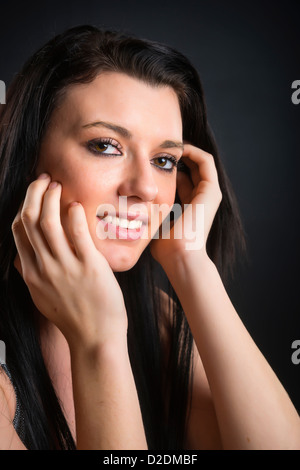 Ritratto di adolescente di sesso femminile con lunghi capelli neri su nero di sfondo per studio, 18 anni, caucasiche Foto Stock