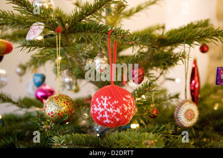 Le decorazioni di Natale appeso a una vera e propria Nordmann abete (Abies nordmanniana) albero di Natale. Lavorato a maglia e baubles di vetro. Foto Stock