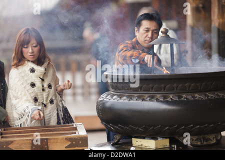 Il popolo giapponese bruciando incenso stick e pregando presso il Tempio di Todai-ji di Nara, Giappone Foto Stock