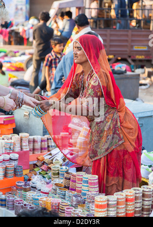 Signora indiana in rosso tipico tradizionale sari abito vendendo schiave a Jodhpur mercato a una pressione di stallo stradale Foto Stock