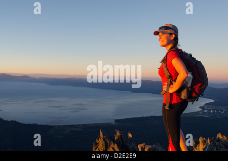 Una femmina di escursionista gode di una spettacolare vista del lago di Tahoe al tramonto dalla cima del monte Tallac, CA. Foto Stock