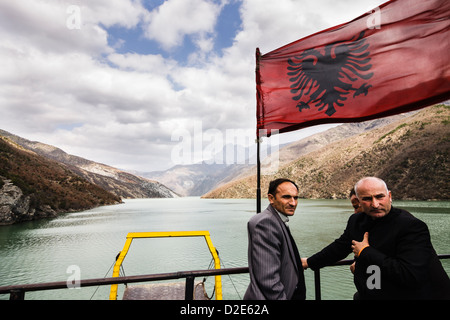 Passeggeri accanto alla bandiera albanese a prua del laghi Komani-Fierze traghetto. L'Albania Foto Stock