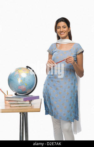 Insegnante femmina tenendo una penna e sorridente Foto Stock
