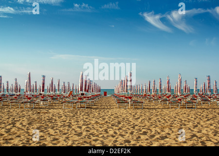 Ritirato ombrelli gialli e sun longers sulla spiaggia sabbiosa in Italia Foto Stock