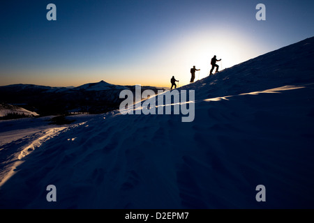 Tre sciatori backcountry stagliano nella bellissima alba luce. Foto Stock