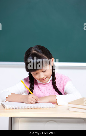 Bella la scolaretta iscritto in aula Foto Stock