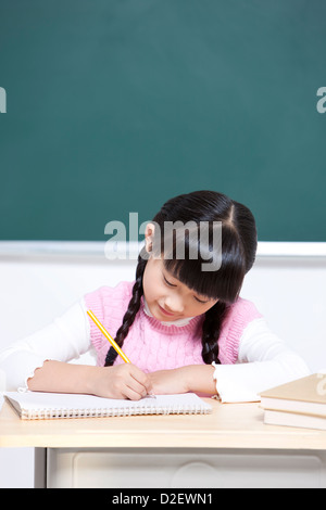 Bella la scolaretta iscritto in aula Foto Stock