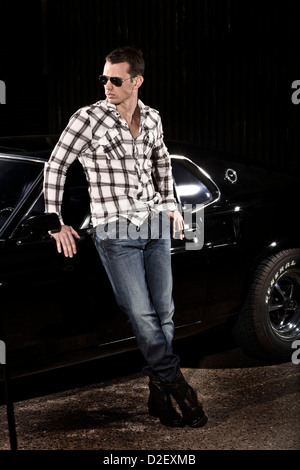 Giovane uomo si erge con nero Ford Mustang Boss 429 auto sportiva Foto Stock