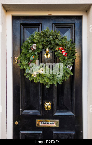 Un tradizionale Natale abete corona appeso su un nero casa porta, Civitanova Marche, regione settentrionale della contea di Dublino, Irlanda Foto Stock