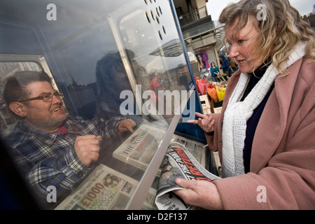 Venditore a vendere lo Scotsman e Edinburgh Evening News quotidiani da una cabina in Princes Street, Edinburgh Foto Stock