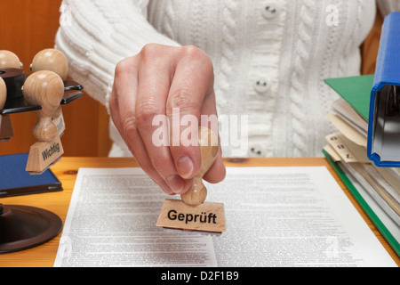 Un timbro con la scritta in tedesco controllato è tenuto in mano Foto Stock