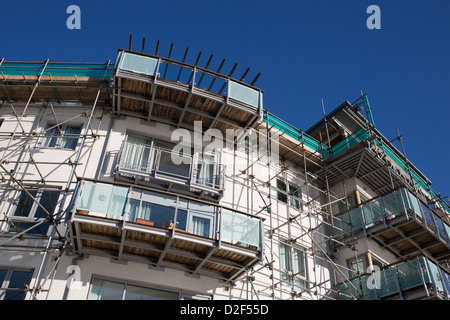 Ponteggio su un blocco di appartamenti che compongono la sede nella zona di porto di Bristol in un giorno chiaro con il blu del cielo. Foto Stock