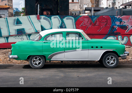 Americano classico anni cinquanta la macchina nella parte anteriore del muro di graffiti per le strade di La Habana, Havana, Cuba Foto Stock