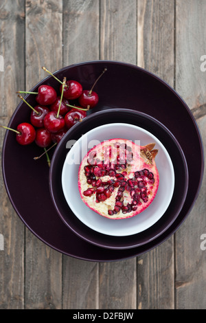 Il Melograno e ciliege in una ciotola. Foto Stock