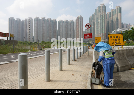 Hong Kong, Cina, una donna in uniforme pulisce la strada Foto Stock