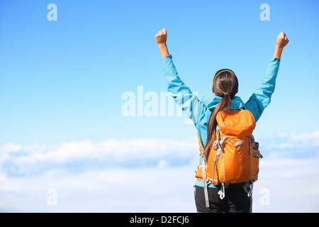 Vista posteriore di un escursionista femmina tifo e beata con le braccia sollevate nel cielo dopo escursioni alla montagna vertice superiore al di sopra delle nuvole Foto Stock