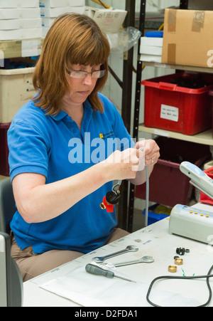 Donna assemblaggio di interruttori elettrici in una fabbrica Foto Stock