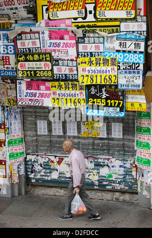 Hong Kong, Cina, vecchio uomo cammina passato un Rollladentor chiuso Foto Stock