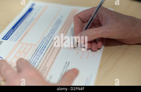 I vecchi donna bianca della mano del riempimento di un modulo ufficiale, tcking caselle e firma la documentazione Foto Stock