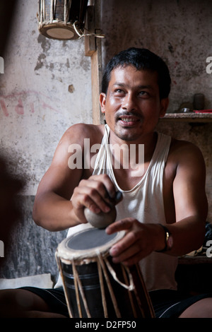 Un piccolo tamburo rendendo la fabbrica in Dhading gestito da marito e moglie, assistiti dai loro nipote. I tamburi sono tradizionali nepalesi. Foto Stock