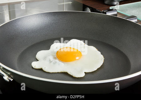 Uovo friggere in una padella su di un piano di cottura in ceramica Foto Stock