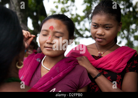 Sanamaya Chepang sta dando Tika ad un paio di giovani donne a un raduno locale in montagna. Foto Stock