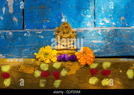Signore Shiva statua e petali di fiori al di fuori del tempio del villaggio porta. India Foto Stock