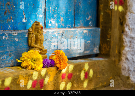 Signore Shiva statua e petali di fiori al di fuori del tempio del villaggio porta. India Foto Stock