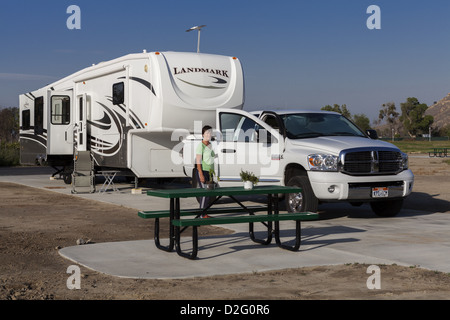 La donna in piedi accanto al camion di espediente e quinta ruota RV in campeggio a Rancho Jurupa County Park, Riverside, California, Stati Uniti d'America Foto Stock