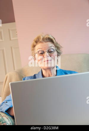 Senior donna utilizzando laptop e sorridente Foto Stock