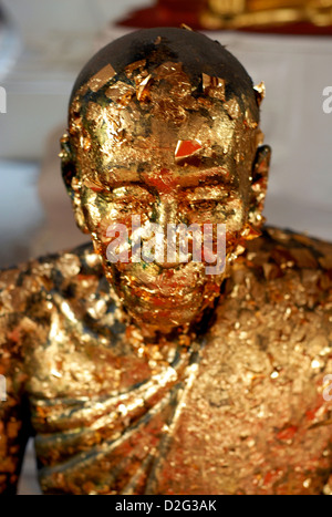 Statua di un monaco ricoperto in foglia oro da fedeli a un tempio a Bangkok in Tailandia Foto Stock