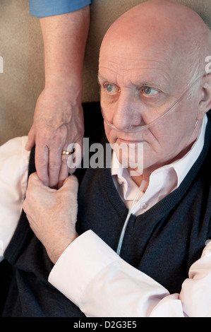 Uomo anziano in una casa di cura con la moglie / caregiver offrendo una confortante mano del supporto Foto Stock