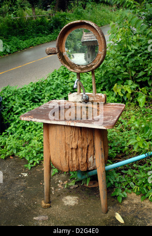 Un dissipatore di lavoro realizzato da un vecchio scavato tronco di albero con uno specchio lungo il lato della strada in Koh Chang thailandia Foto Stock