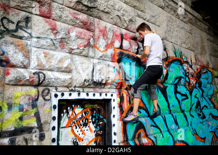 Un scalatore pratiche le sue tecniche su un fiume parete lungo il Danubio a Vienna, in Austria Foto Stock