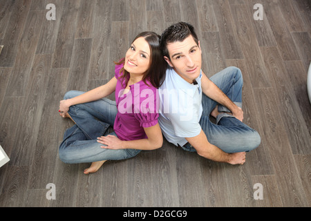 Giovane seduto sul pavimento in laminato Foto Stock
