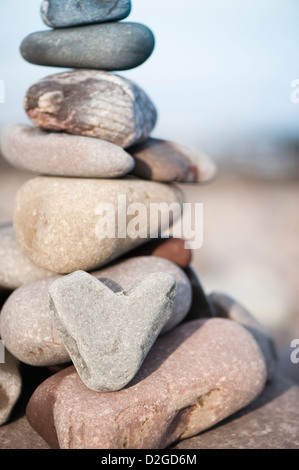 Di pietra a forma di cuore con una pila di pietre sulla spiaggia a Porlock Weir, Somerset, Inghilterra, Regno Unito Foto Stock