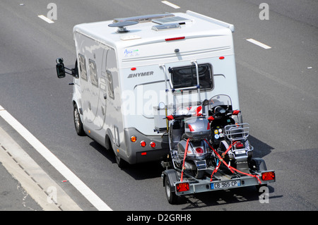 Camper van traino di un rimorchio con due scooter percorrendo l autostrada M25, Essex England Regno Unito Foto Stock