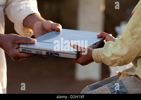 India Rajasthan, Jodhpur, tribesman la mano ricevendo il laptop dal giovane ragazzo in mano Foto Stock