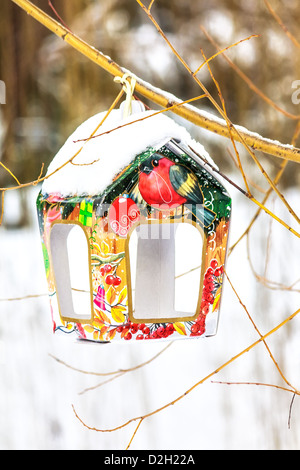 Coperte di neve birdfeeder colorati sul tronco di albero Foto Stock