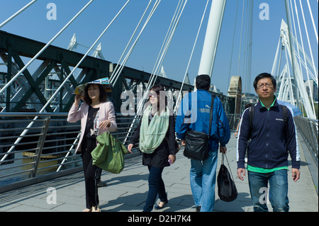 Londra, Southbank, Riverside, Embankment, Hungerford Bridge pendolari turisti attraversando a piedi il ponte in una giornata di sole Foto Stock