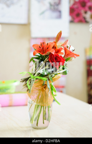 Bouquet di fiori in un bicchiere sul tavolo Foto Stock