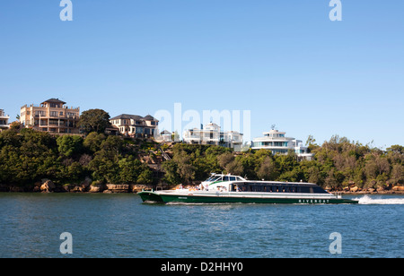 'Dawn Fraser' Parramatta RiverCat passando case di lusso sul lungomare a Fern Bay Porto di Sydney Australia Foto Stock