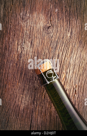 Parte superiore della bottiglia di champagne con sughero sul vecchio sfondo di legno. Foto Stock