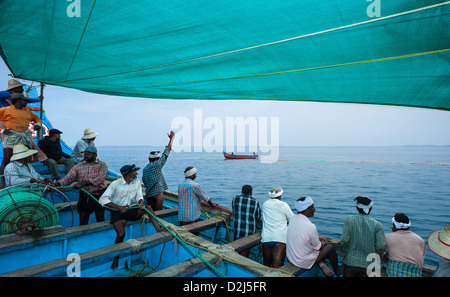 Deep sea pescatori preparare al raggio in una grande rete da pesca pieno di sardine da loro imbarcazione in legno, Kannur, Kerala, India. Foto Stock