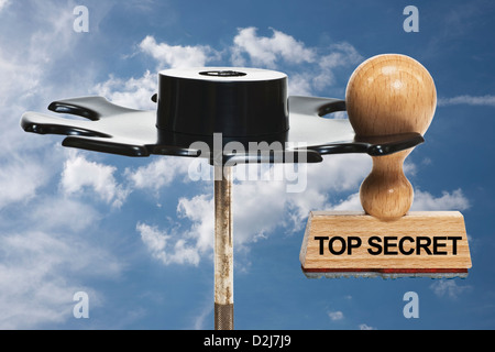 Un timbro con la scritta top secret si blocca in un rack di timbro, sfondo Cielo e nubi Foto Stock